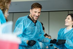 Medical professionals in blue protective gear share a lighthearted moment during training.