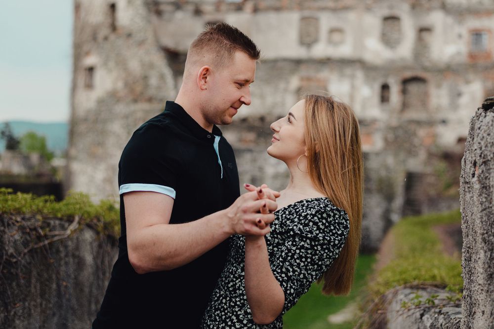 Romantic couple poses in front of ancient castle ruins during engagement shoot.