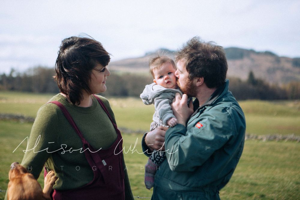A family moment captured outdoors with rolling hills in the background.