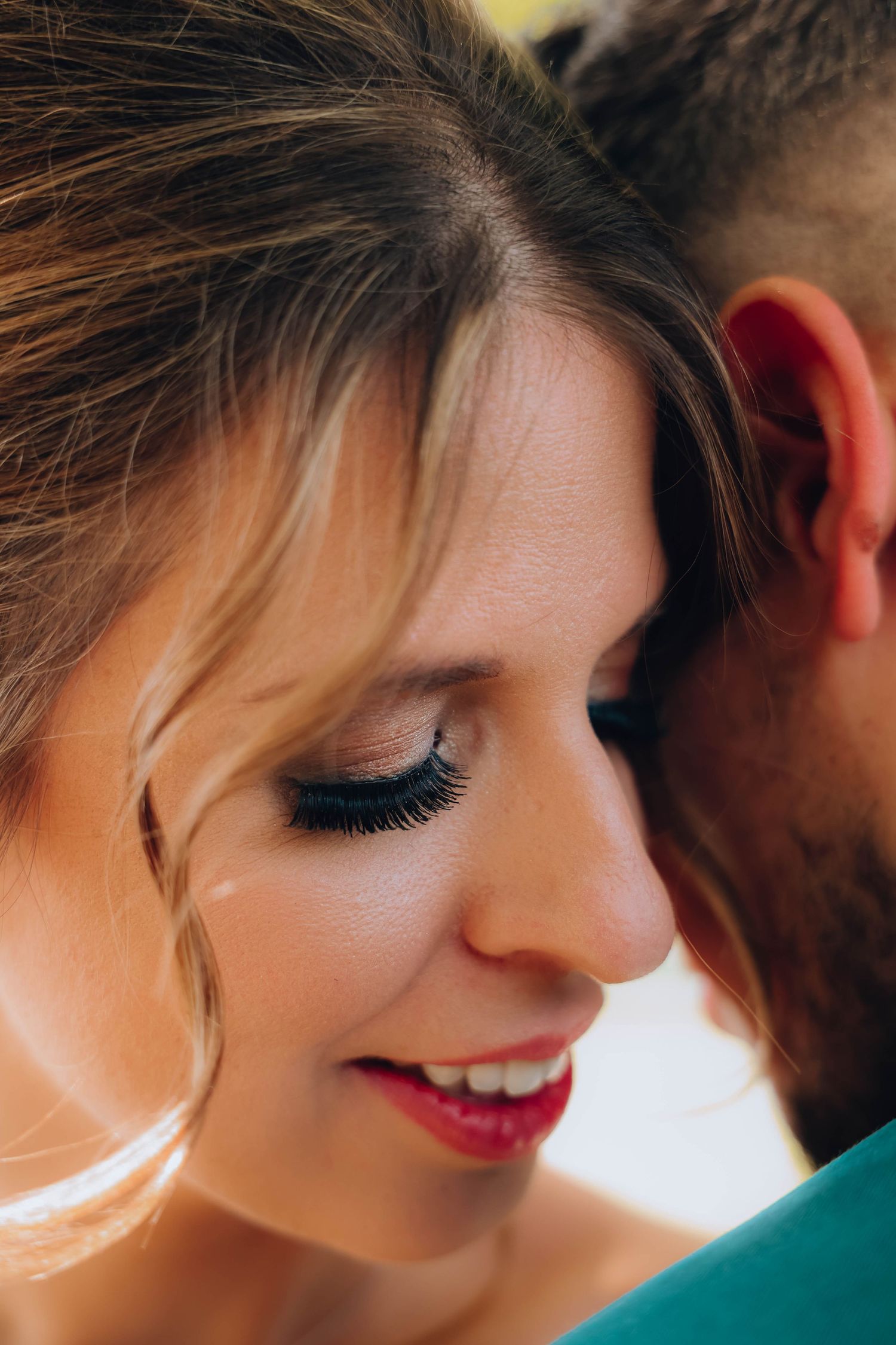 Close-up detail of bridal makeup with sparkling eyeshadow and soft romantic smile.
