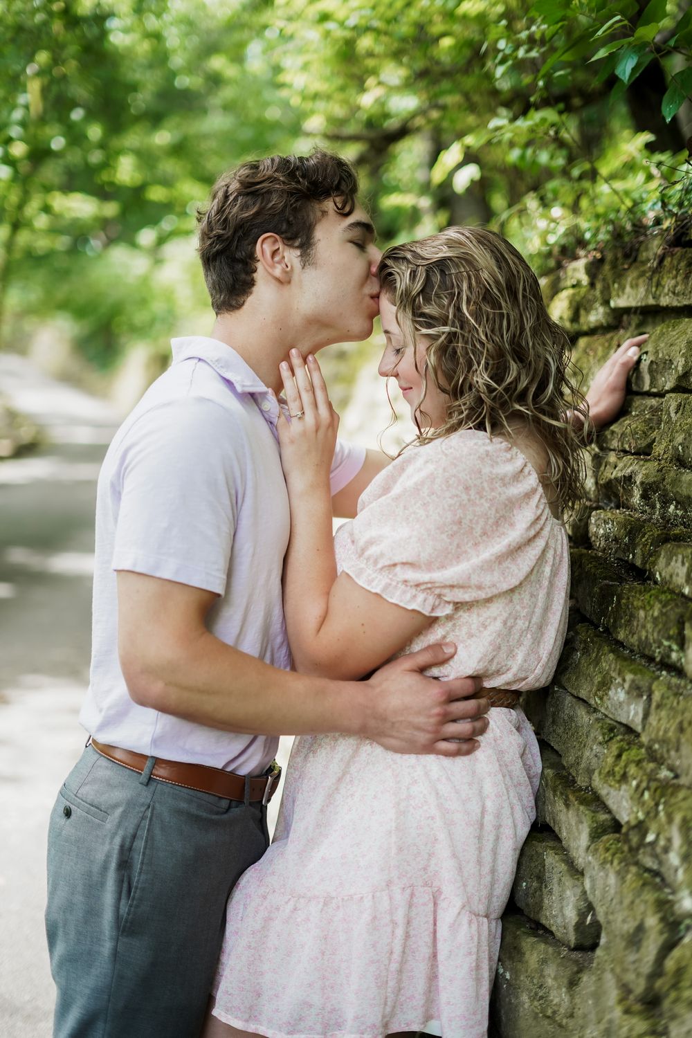 A romantic moment shared against a stone wall backdrop in a garden setting.