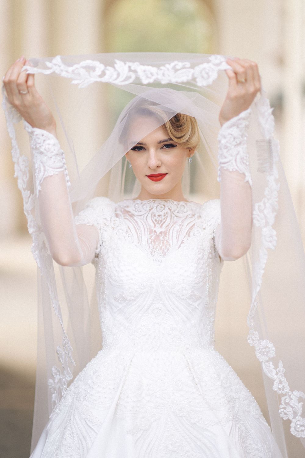 A classic bridal portrait featuring a white lace gown and delicately embroidered veil.