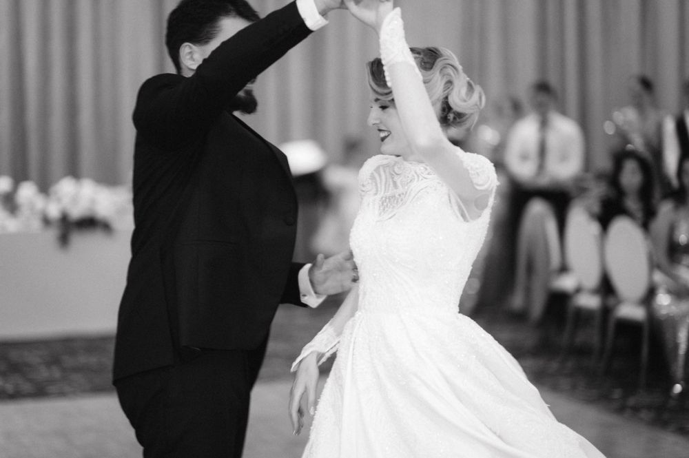 A black and white photo capturing a joyful moment during a wedding first dance.