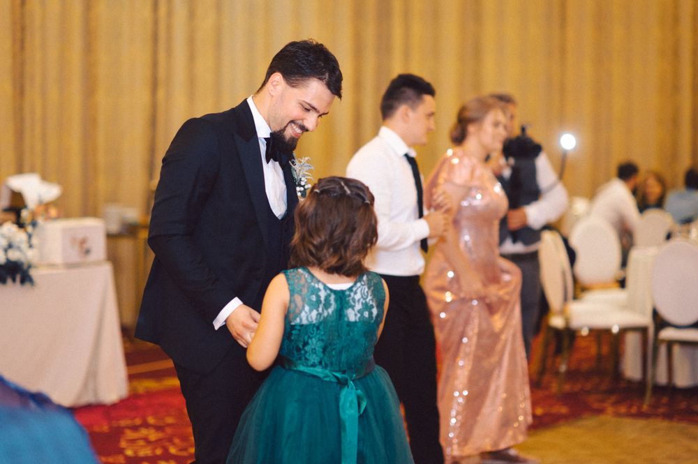 A couple shares a dance with a young guest in a teal dress during a wedding reception.