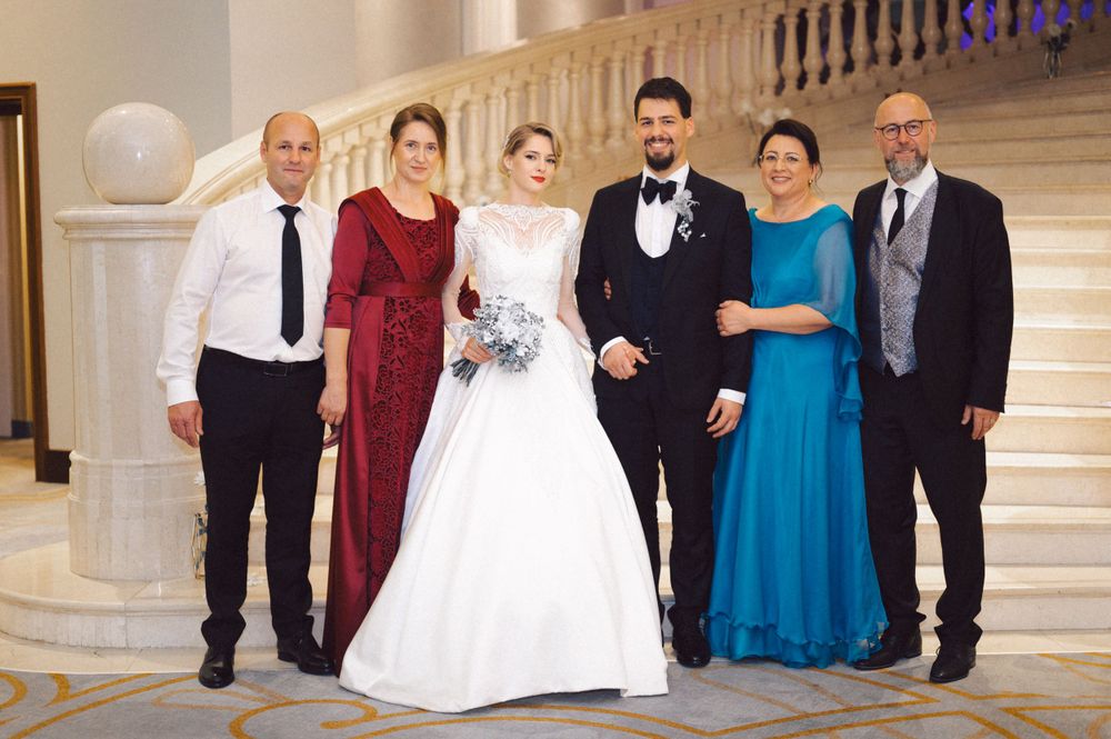 A formal wedding party group photo on elegant marble stairs in the venue.