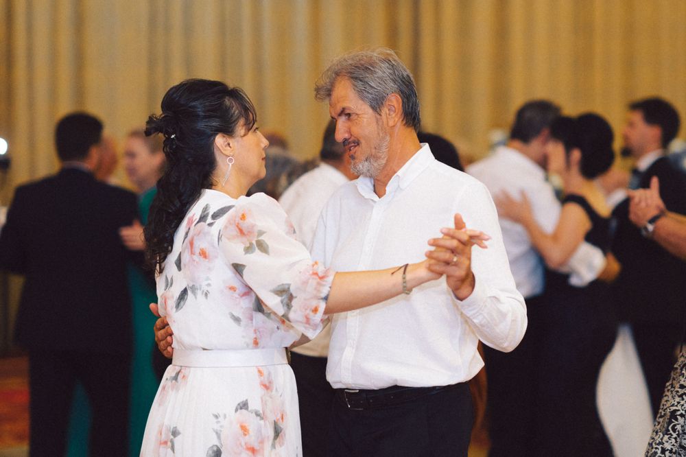 Couples dancing together at a wedding reception with gold curtains in the background.