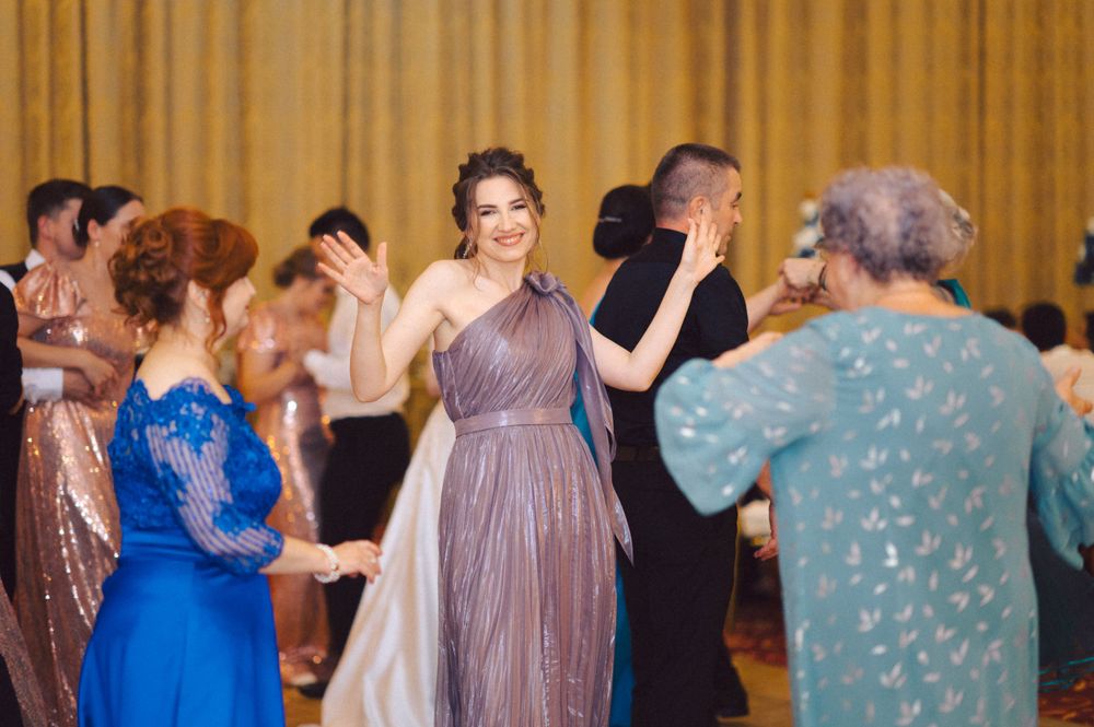 Wedding guests dancing and celebrating in elegant dresses at a formal reception.