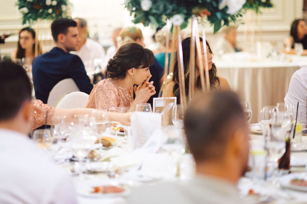 Reception guests enjoying dinner at elegantly decorated tables.