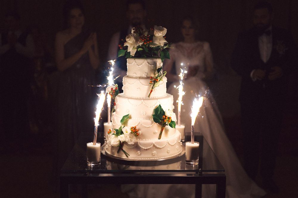 Wedding cake with sparkler fountains displayed in dramatic lighting.