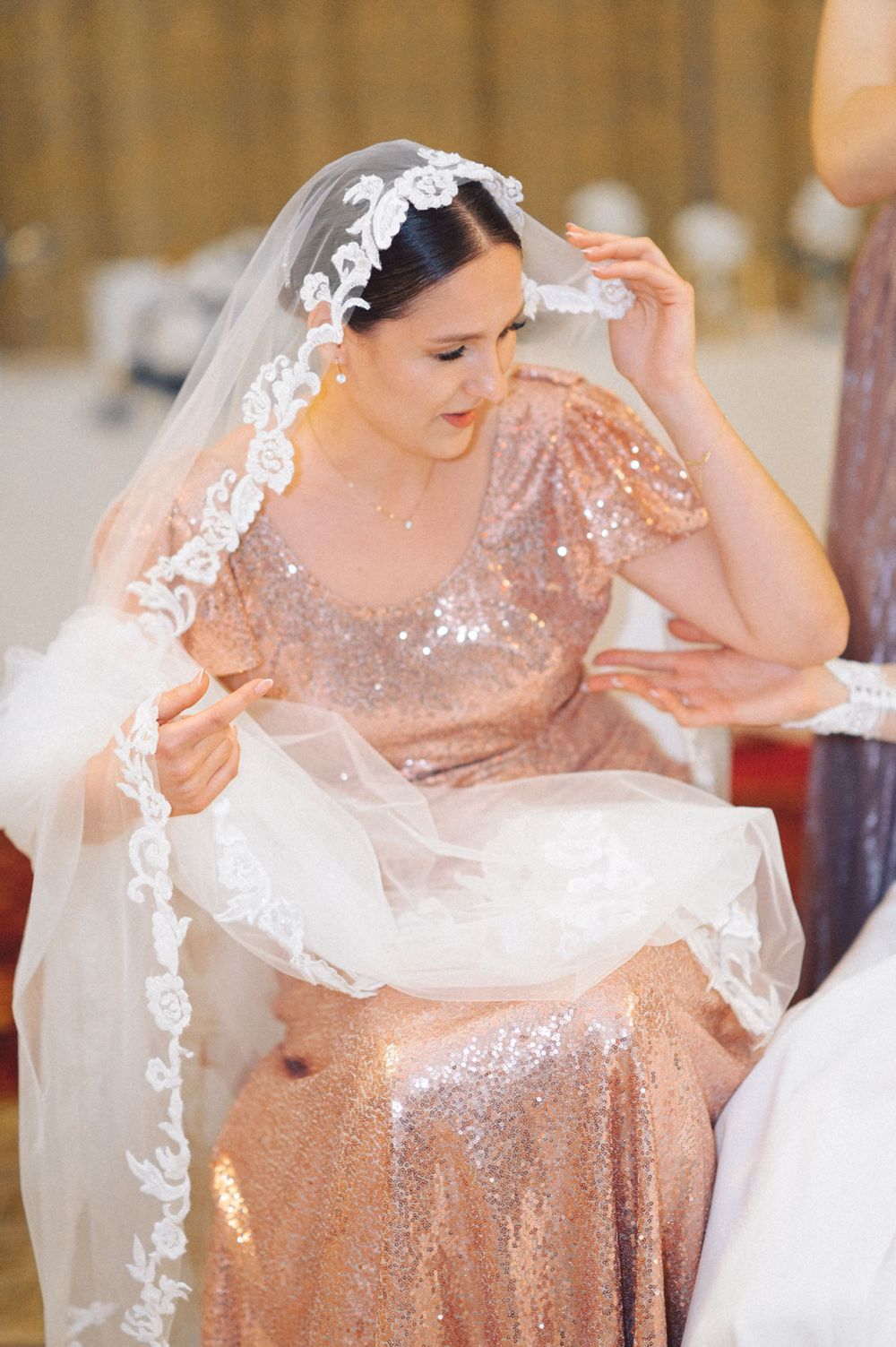Sparkling rose gold dress and delicate lace veil details at a wedding celebration.