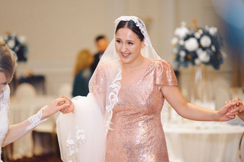 Wedding celebration with attendee in shimmering rose gold sequin dress and veil.
