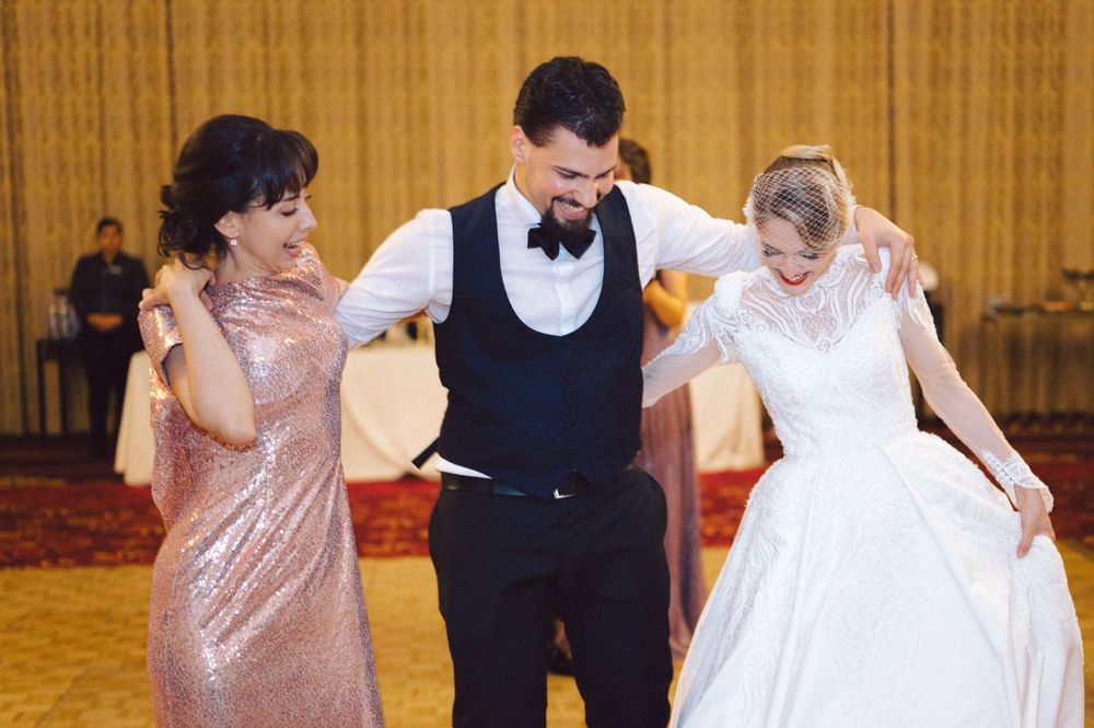 Wedding party dancing together in formal attire on wooden dance floor.