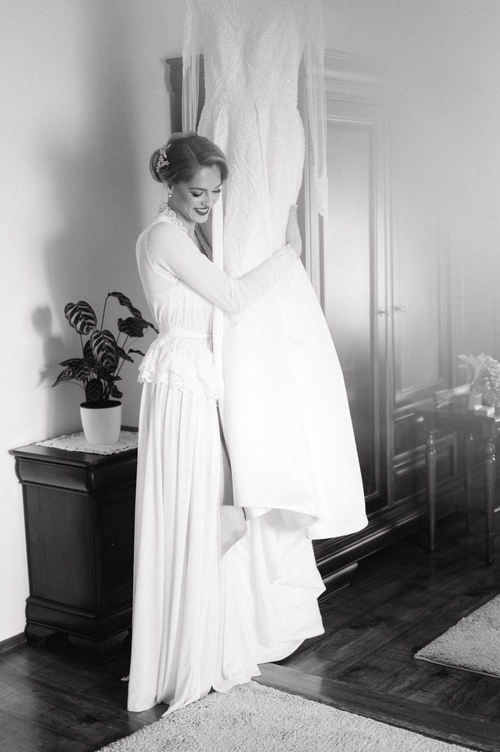 Vintage black and white photo showing preparation of wedding dress hanging in elegant room.