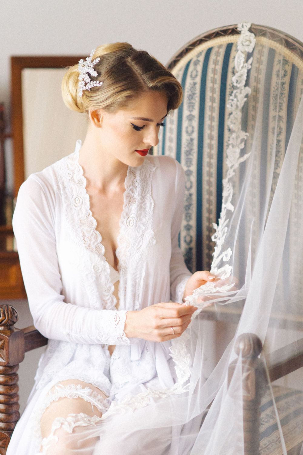 Classic bridal boudoir scene with delicate white lace robe and elegant decor.