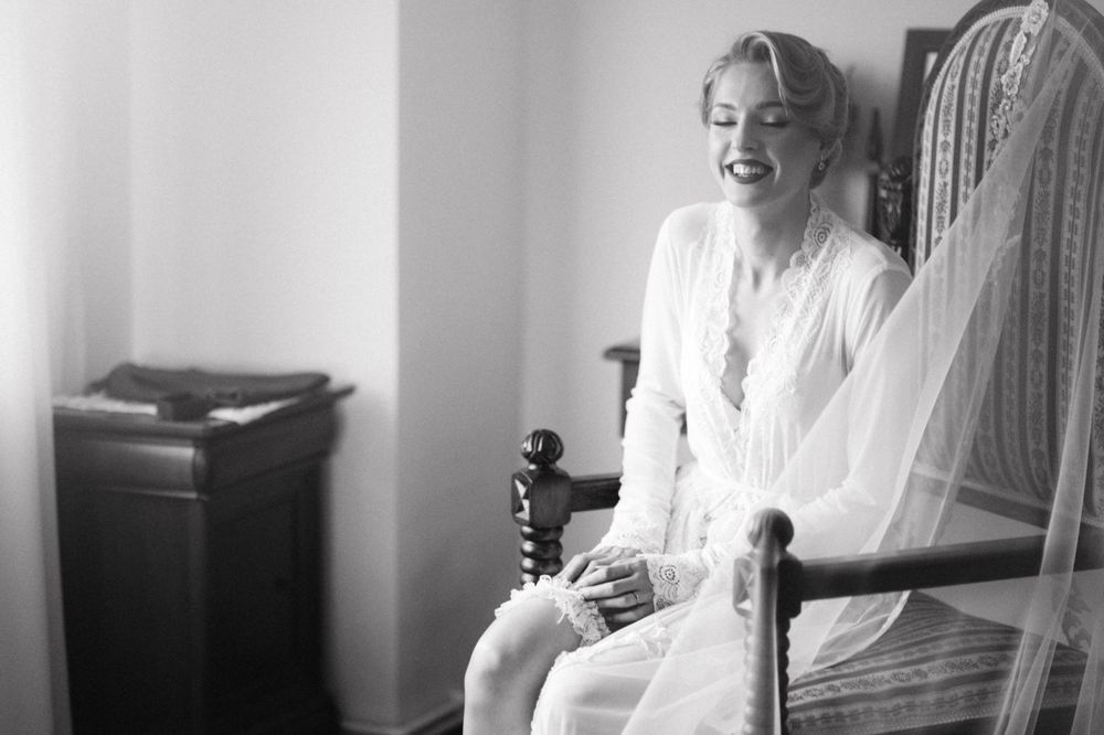 Black and white candid moment of bridal preparation in vintage setting.
