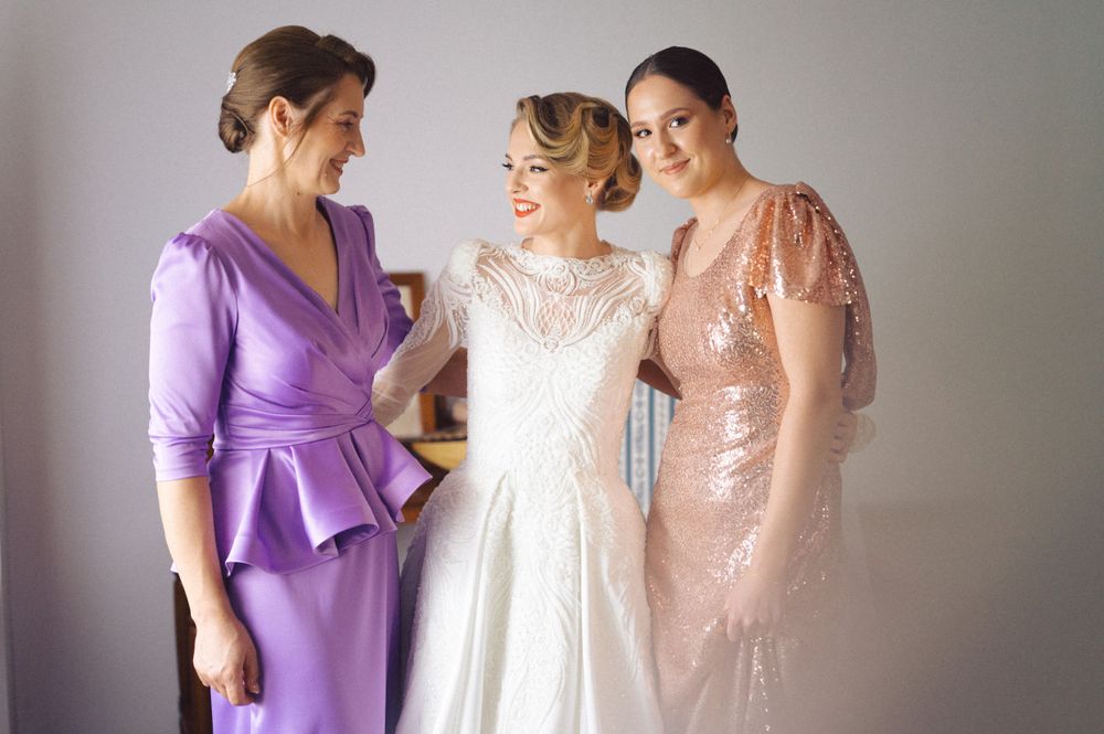 Group photo of wedding party members wearing purple, white, and rose gold gowns.