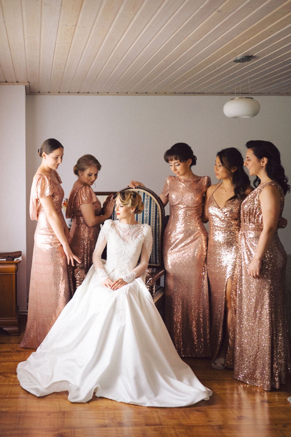 Wedding party poses together with bridesmaids in rose gold sequin dresses surrounding bride in classic white gown.