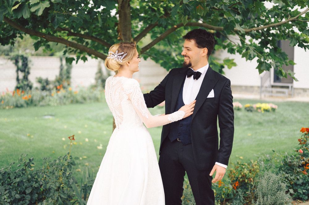 Intimate outdoor wedding moment between couple surrounded by lush garden scenery.