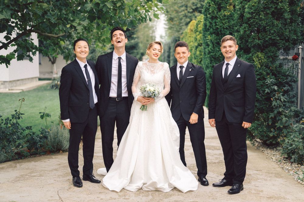Wedding party of five people in formal attire posing outdoors.