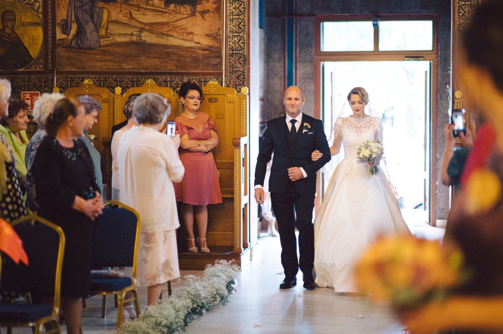 Wedding ceremony entrance procession in elegant wood-paneled room with floral decorations.