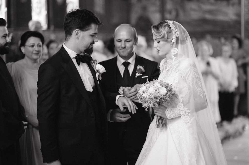 Black and white photo of traditional wedding ceremony moment in church setting.