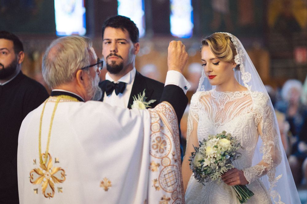 Orthodox wedding ceremony with priest in ornate gold-trimmed vestments and couple at altar.
