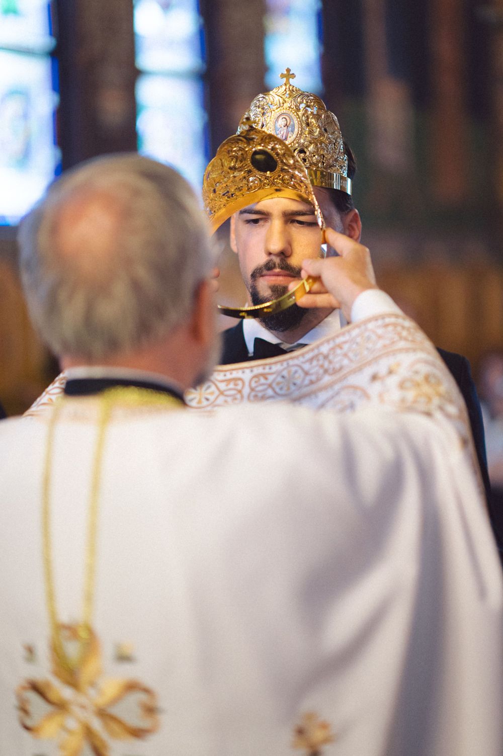 Orthodox priest performs traditional crown blessing ritual during wedding ceremony.