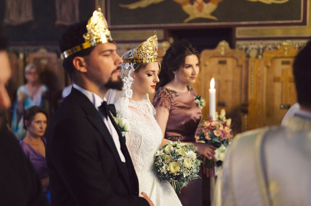 Wedding couple wearing ceremonial crowns during traditional Orthodox marriage ceremony.