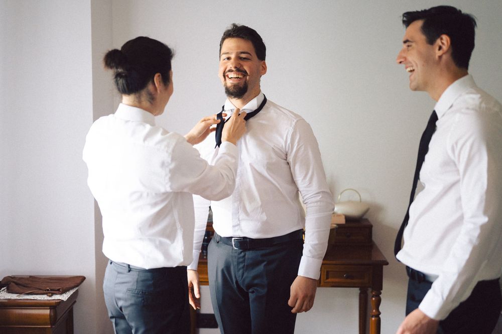 People in formal attire helping each other with bow ties and getting dressed.