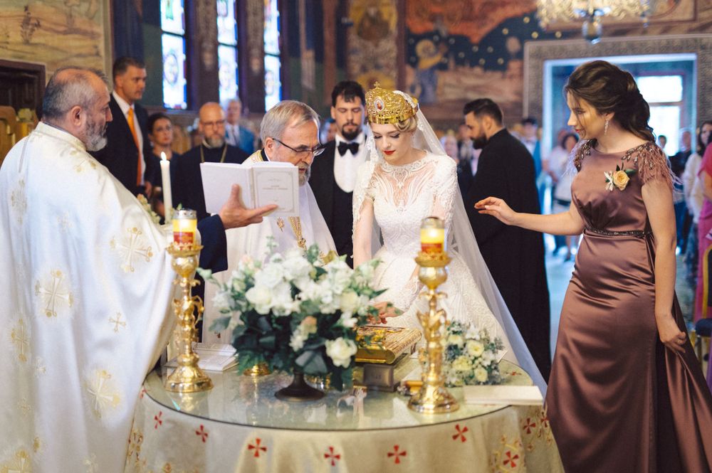 Orthodox wedding ceremony with priests and attendants gathered around decorated altar table with candles.