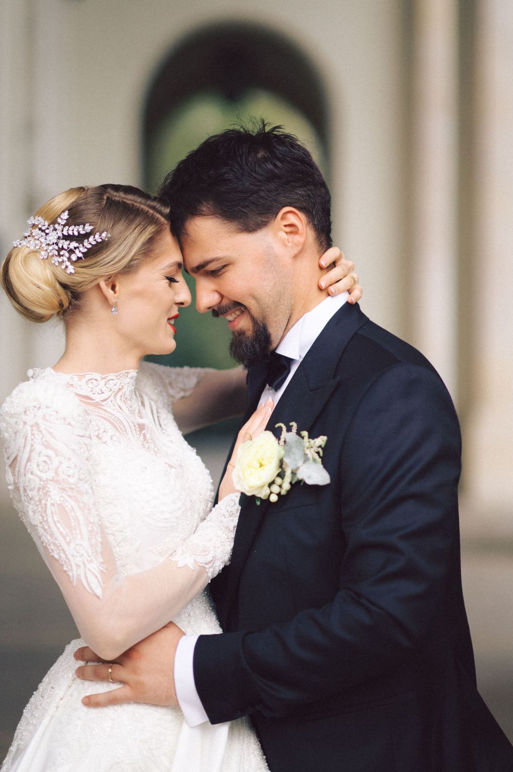 Intimate wedding portrait showing a romantic moment between newlyweds, with bride in lace dress and groom in classic tuxedo.