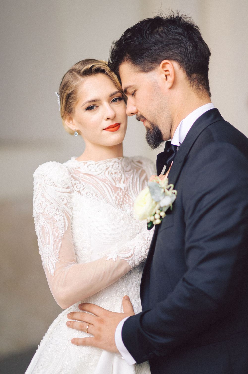 Romantic close-up of newlyweds sharing tender moment, bride wearing delicate lace gown and crystal hairpiece.