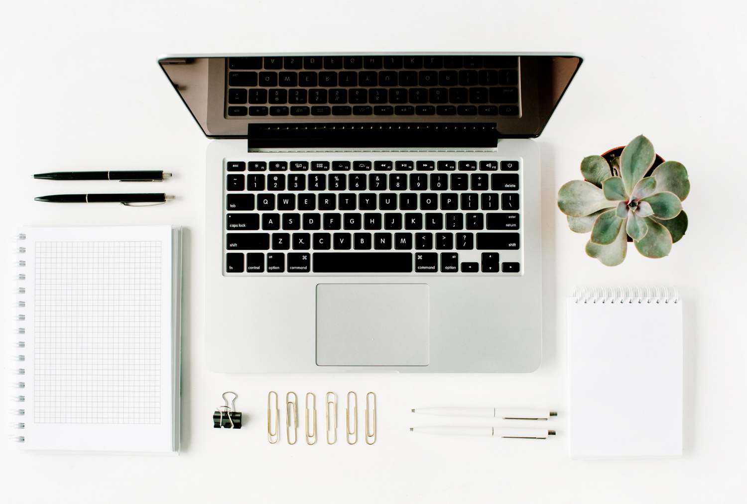 Flat lay of MacBook, notebooks and some stationery