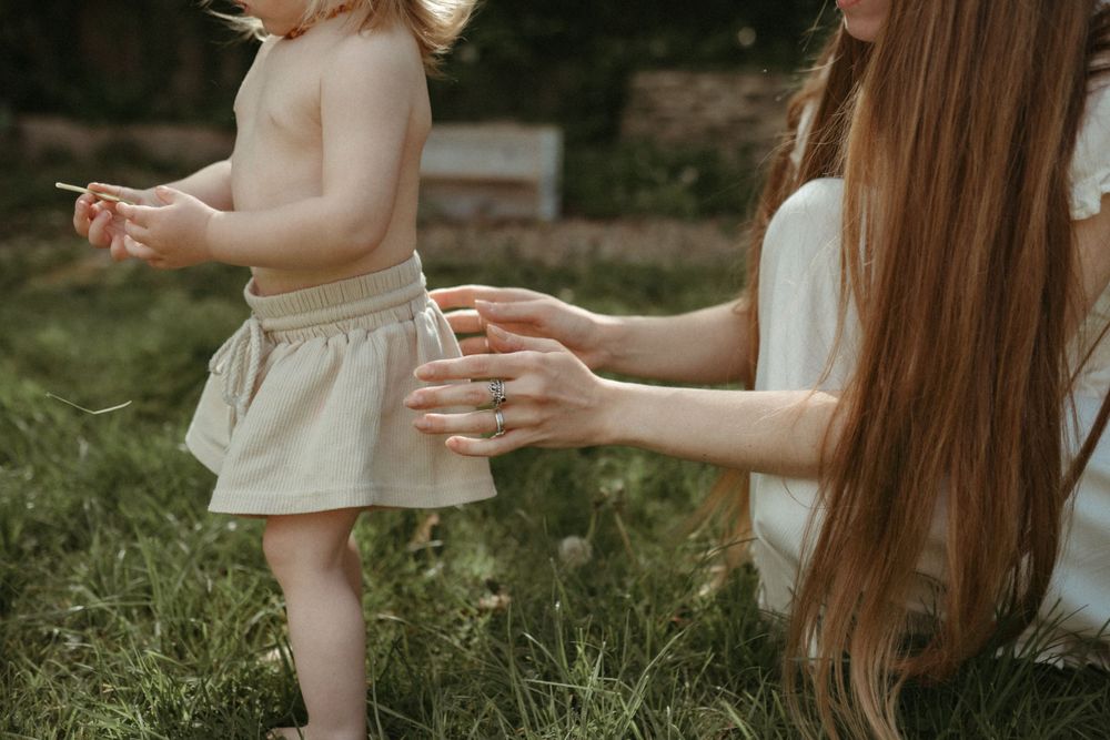 Parent and toddler sharing a tender moment in a sunny garden setting.