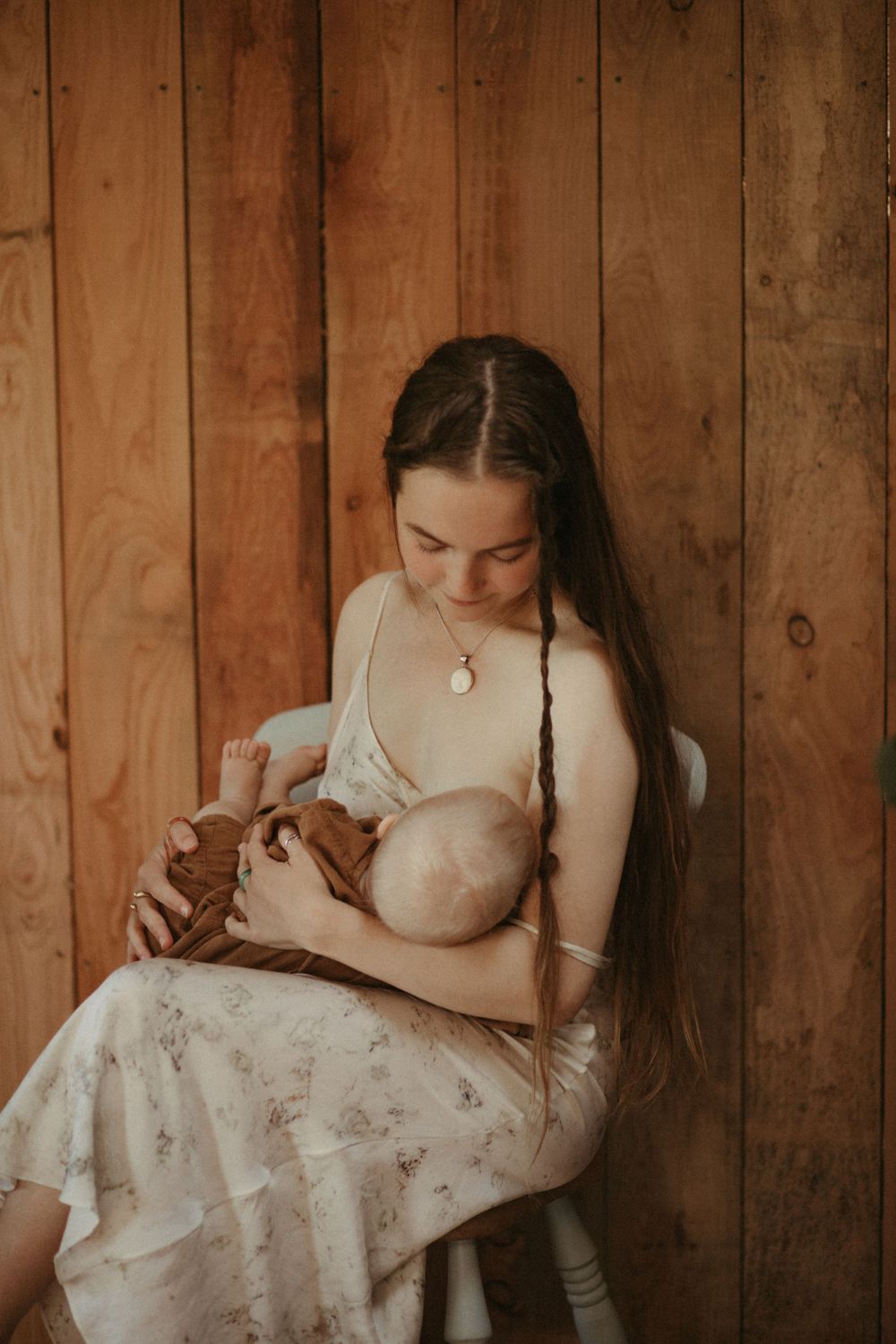 Intimate nursing portrait against rustic wooden wall background.