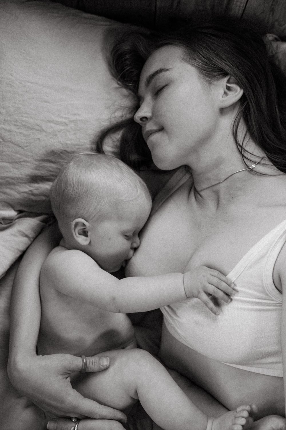 Intimate black and white photograph of nursing moment between parent and infant.