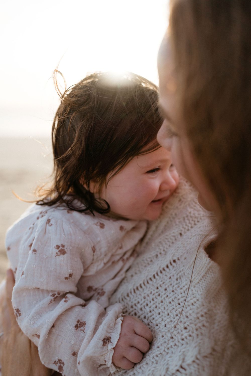 Intimate sunlit moment between parent and child in warm light.