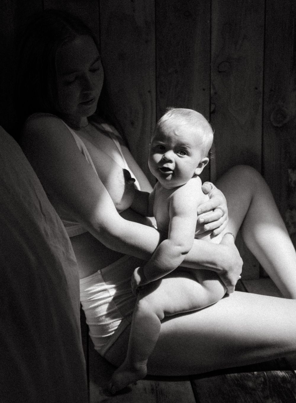 Black and white portrait of joyful infant with parent in natural light.