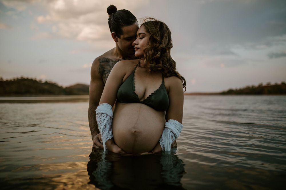 Couple in the water embracing baby bump at Lake Moondarra, Mount Isa