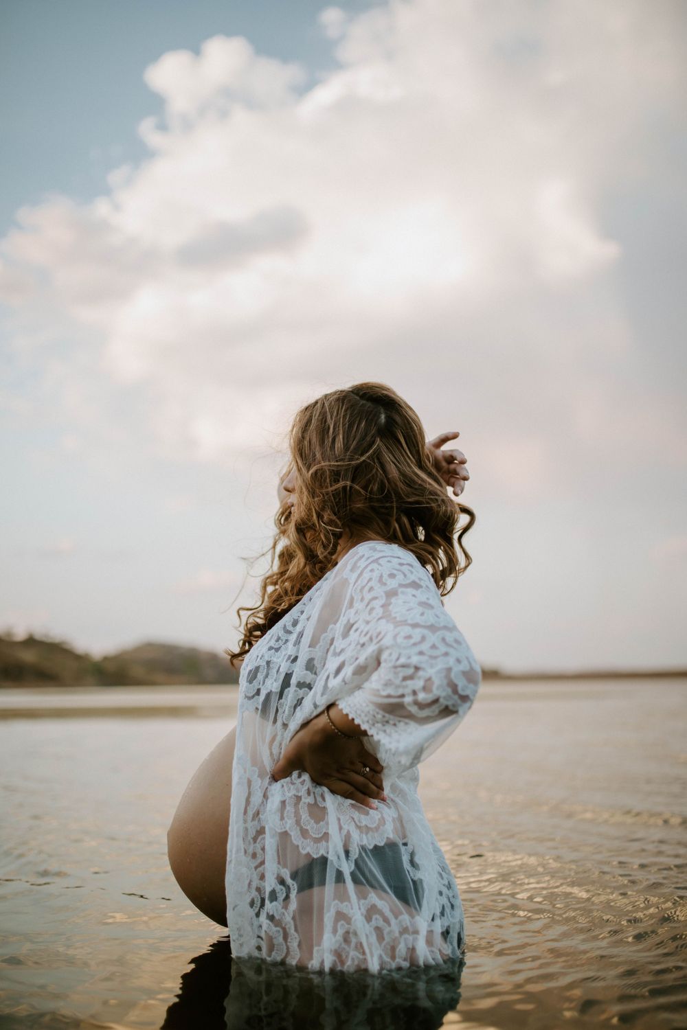 Image of mama to be embracing belly while standing in water at Lake Moondarra, Mount Isa
