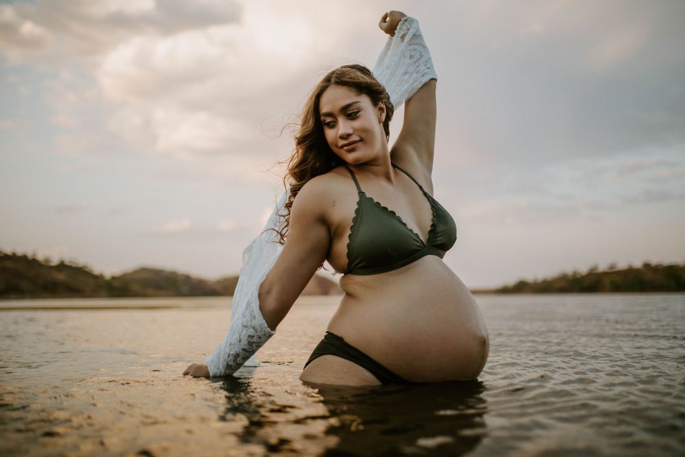 Mama to be embracing wind while standing in water at Lake Moondarra, Mount Isa