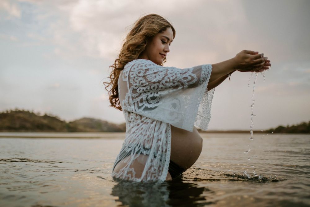 Image of mama to be embracing belly while standing in water at Lake Moondarra, Mount Isa