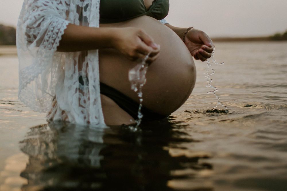 Close up of image of mama to be embracing belly while standing in water at Lake Moondarra, Mount Isa