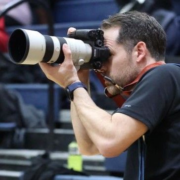 Professional photographer using a long telephoto lens to capture sports or wildlife photography.