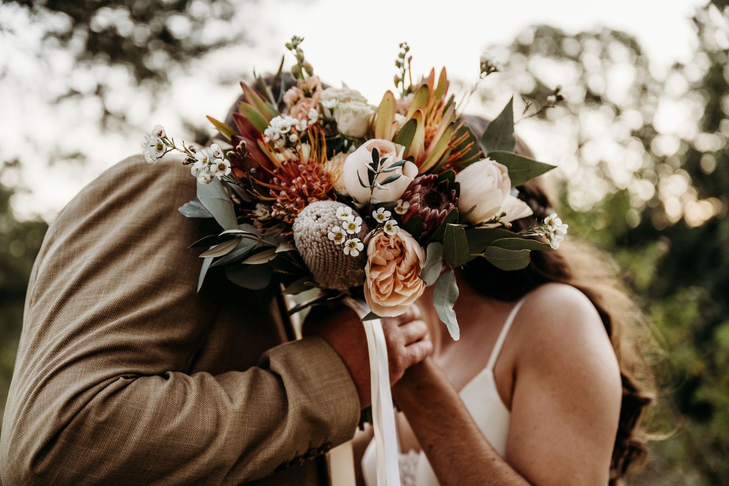 Romantic moment with wedding bouquet featuring dried flowers and autumn colors.