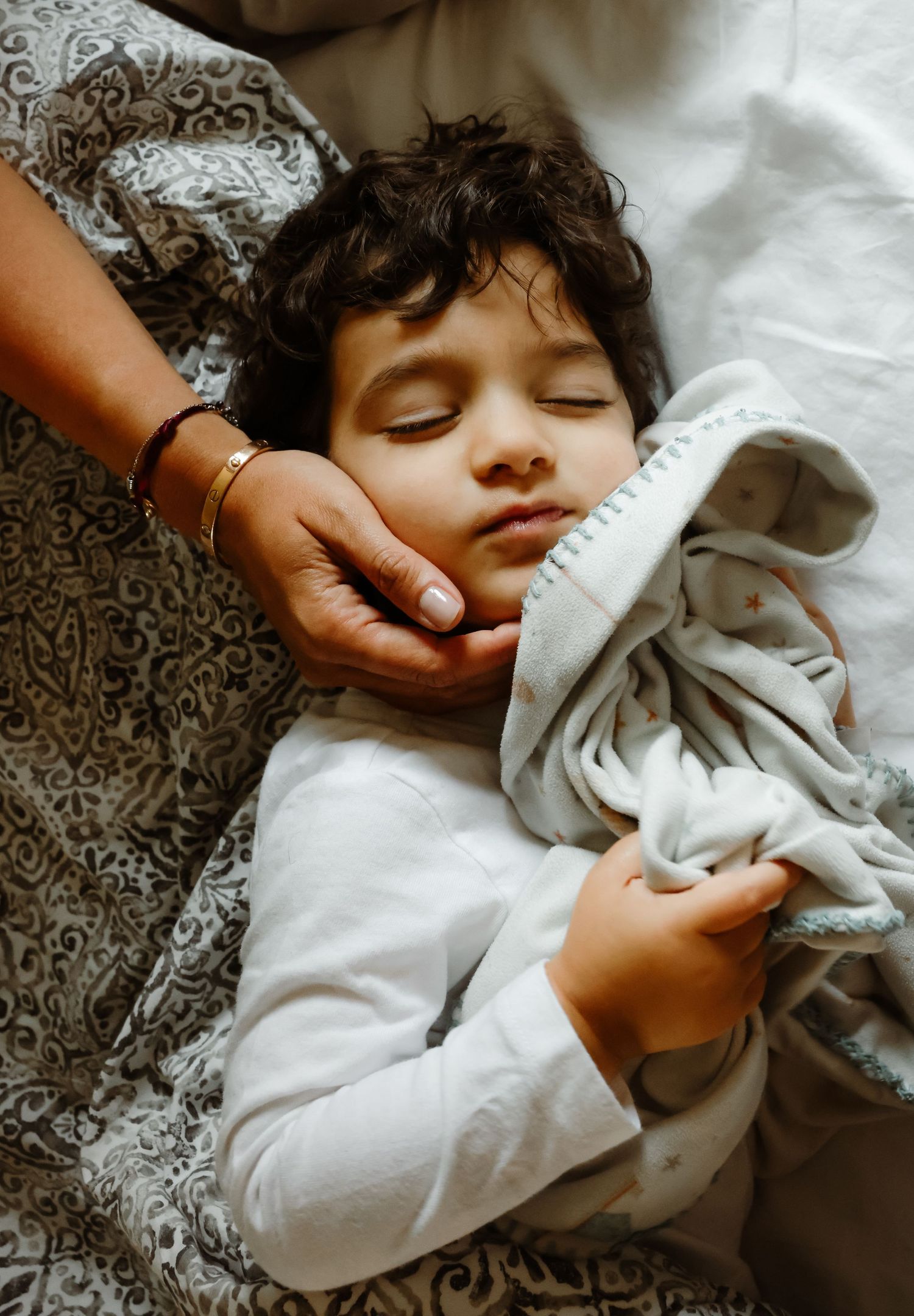A peaceful sleeping child wrapped in soft blankets while being comforted.