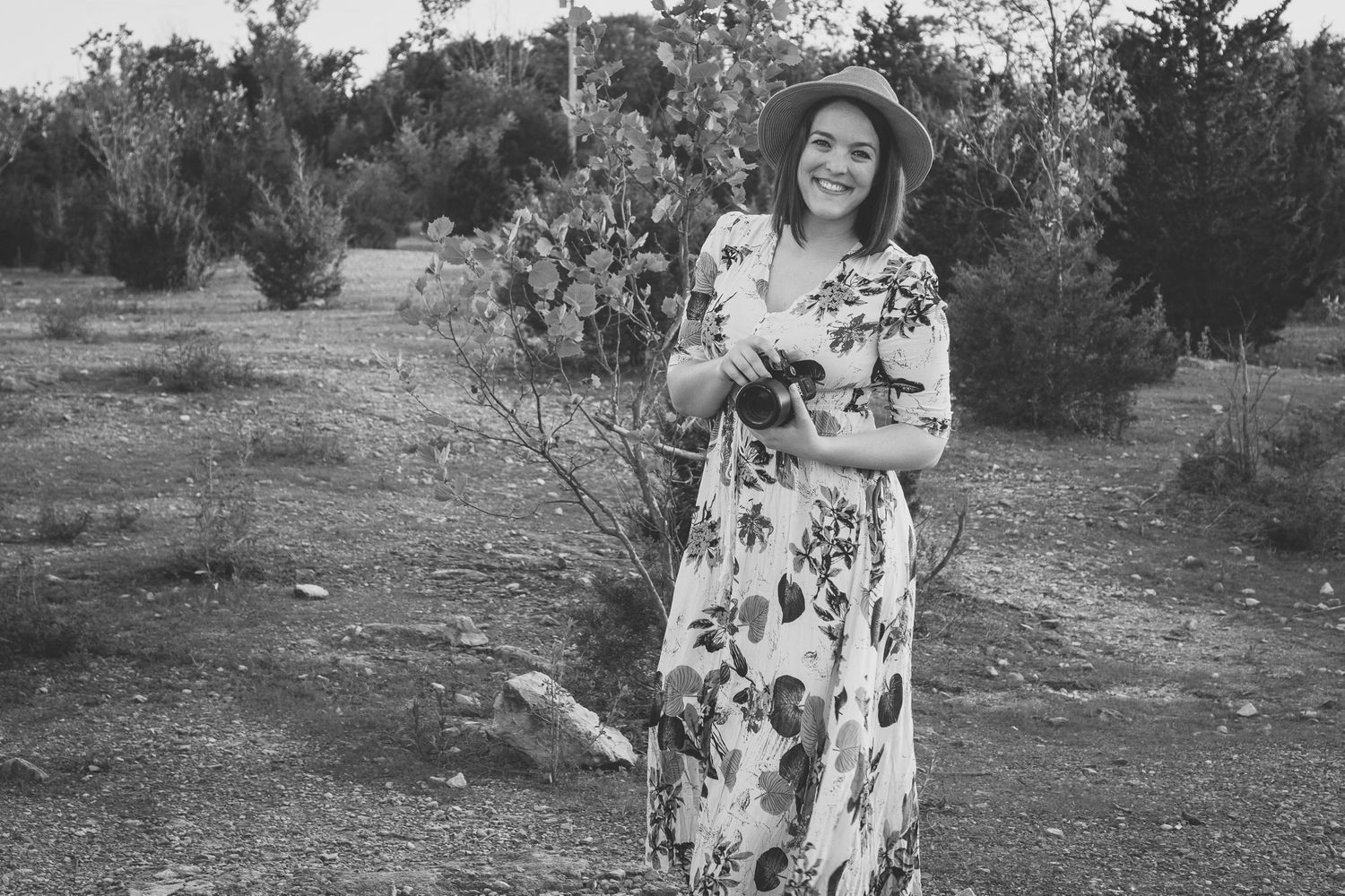 Black and white image of a photographer holding camera and smiling