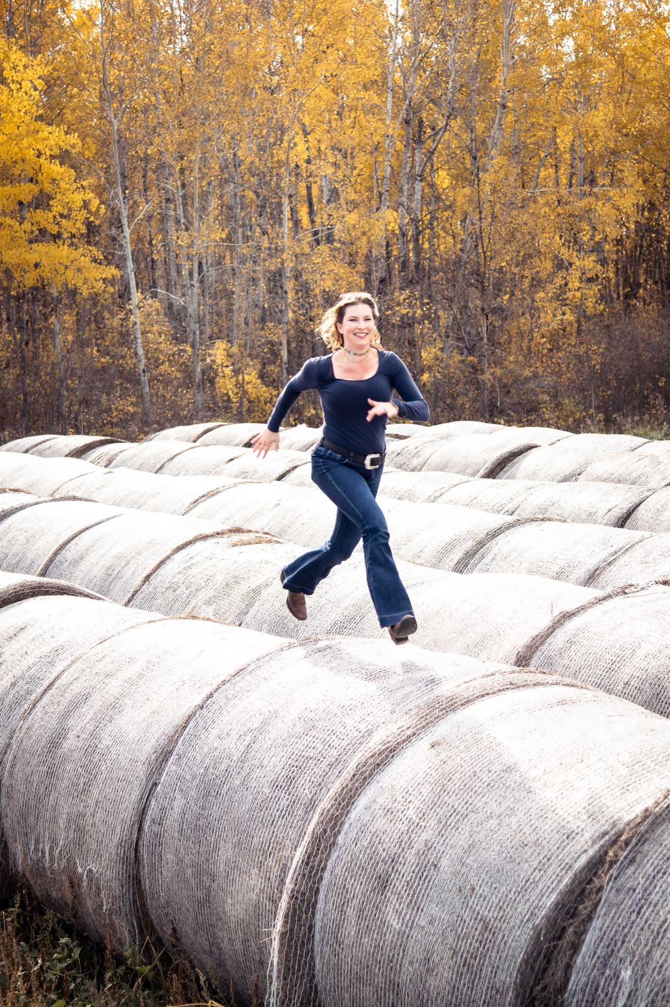 Farmer woman running on Hay bales, fall, near Steinbach Manitoba