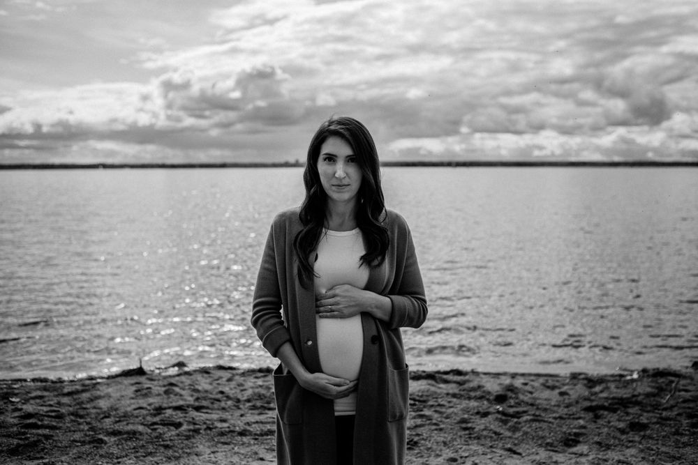 Dramatic black and white maternity portraits captured along a moody shoreline.