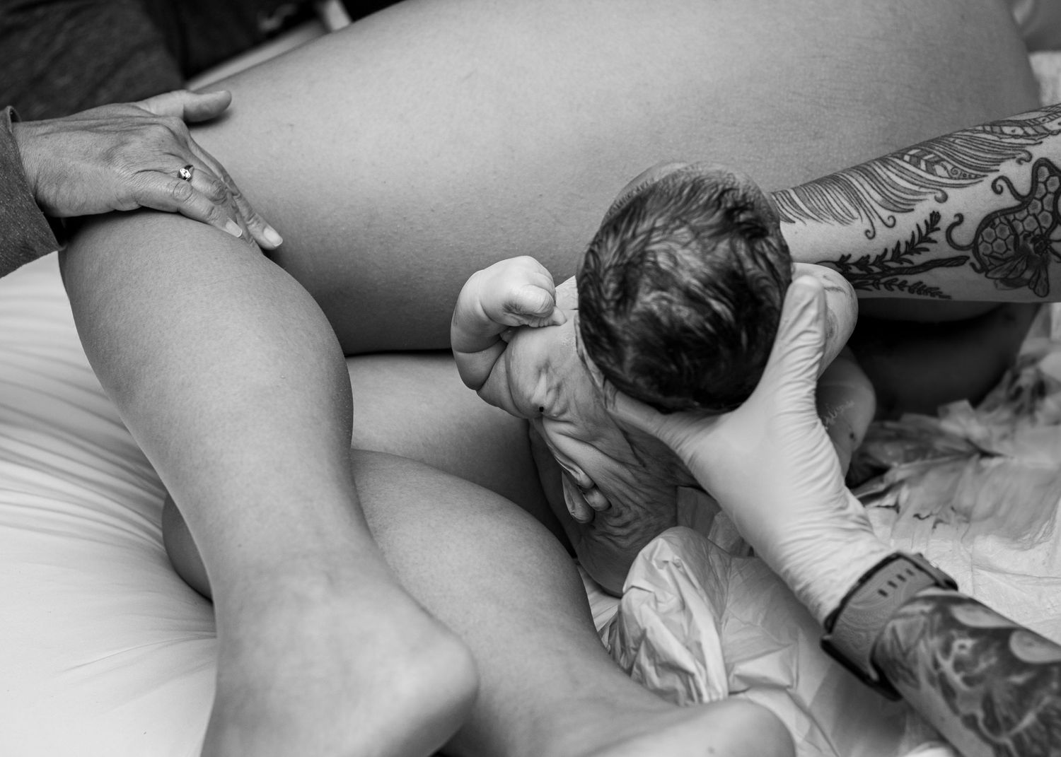 Black and white image capturing an intimate moment with a newborn during birth.